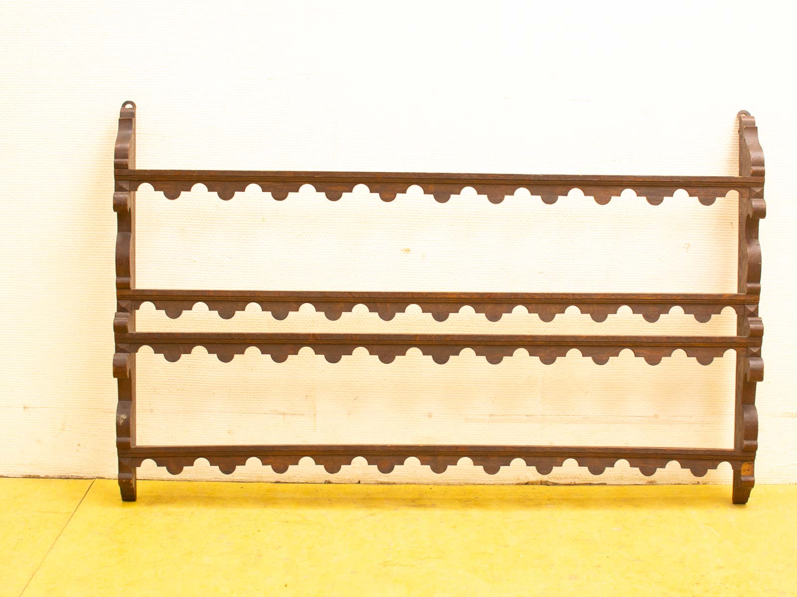 Elegant dark wood rack with scalloped edges, ideal for showcasing books and decor.