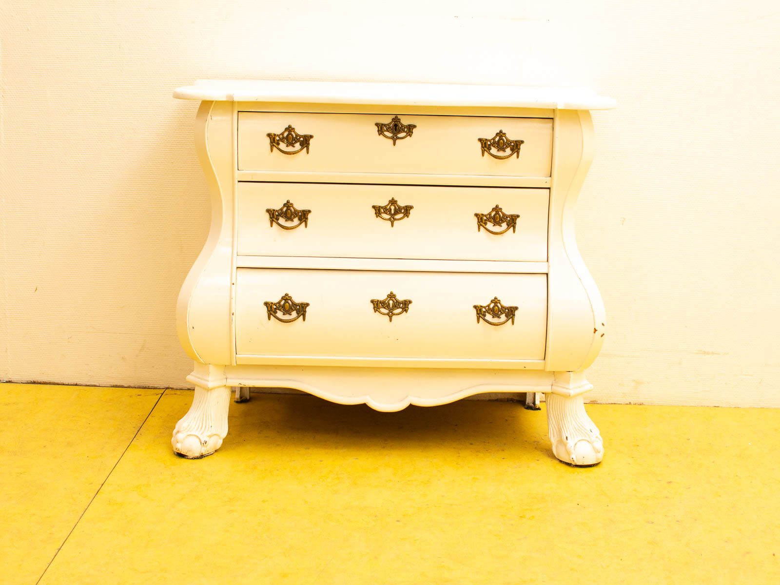 Elegant vintage white nightstand with brass handles and unique paw-shaped feet. Perfect for any decor.