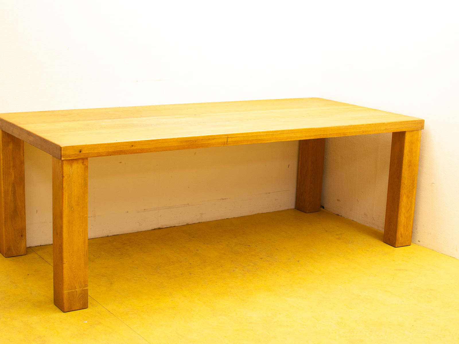 Modern wooden table on cheerful yellow floor against a white wall in a minimalist setting.