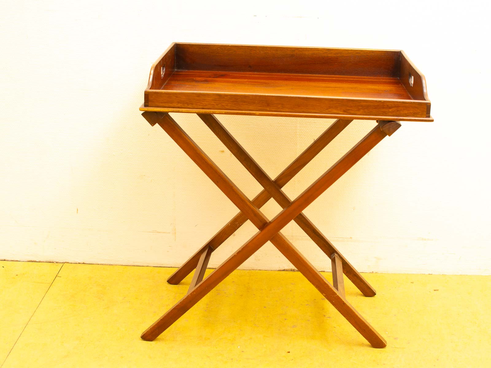 Elegant wooden tray table with crossed legs, perfect for serving and space-saving.