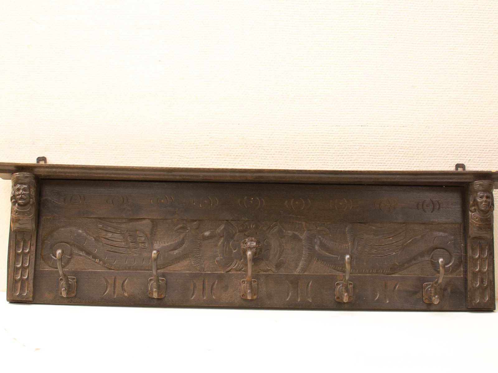 Intricate wooden wall hook with mythical dragons and figures, blending art and functionality.