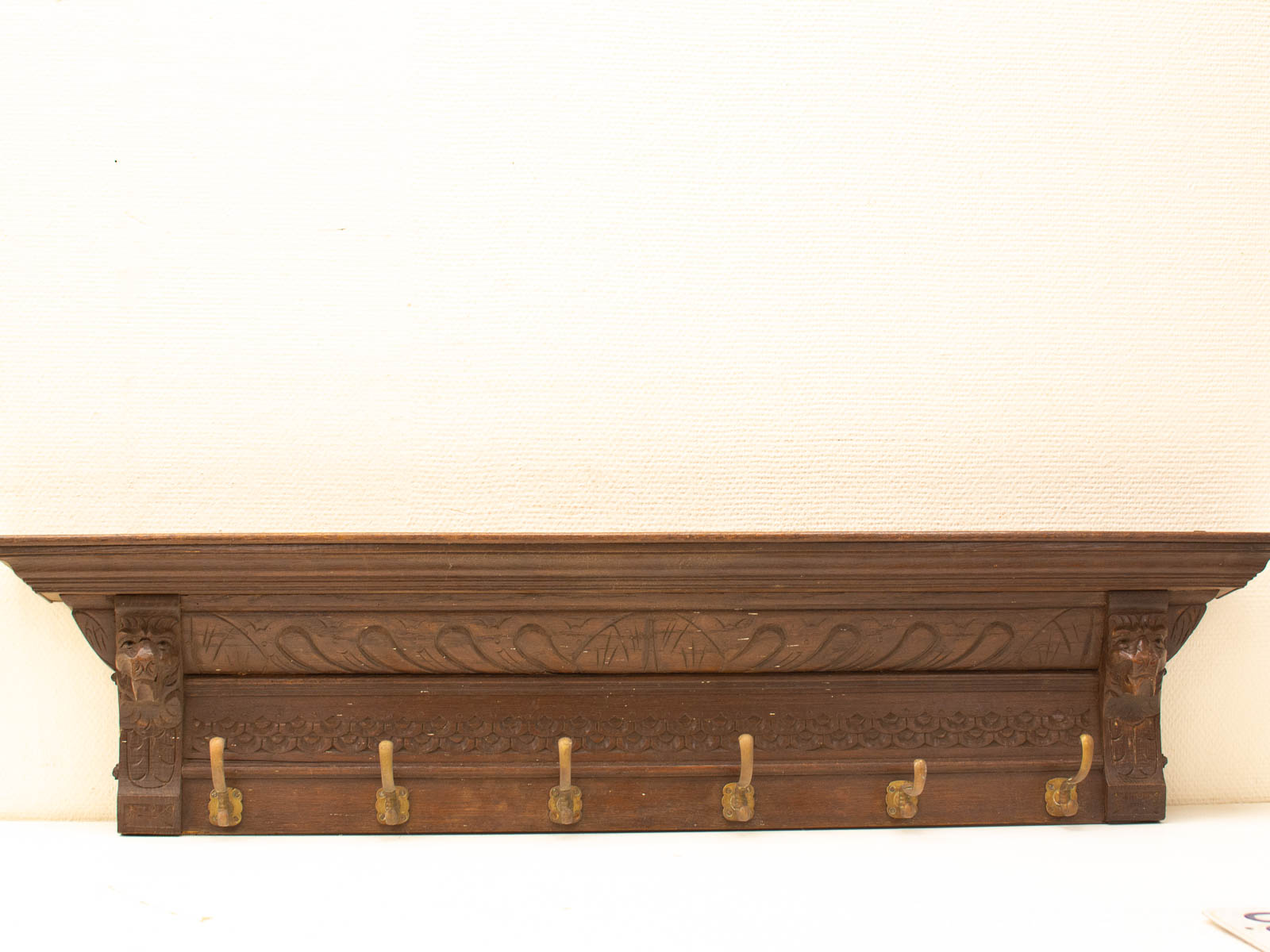 Elegant wooden coat rack with ornate carvings and stylish brass hooks for any interior.