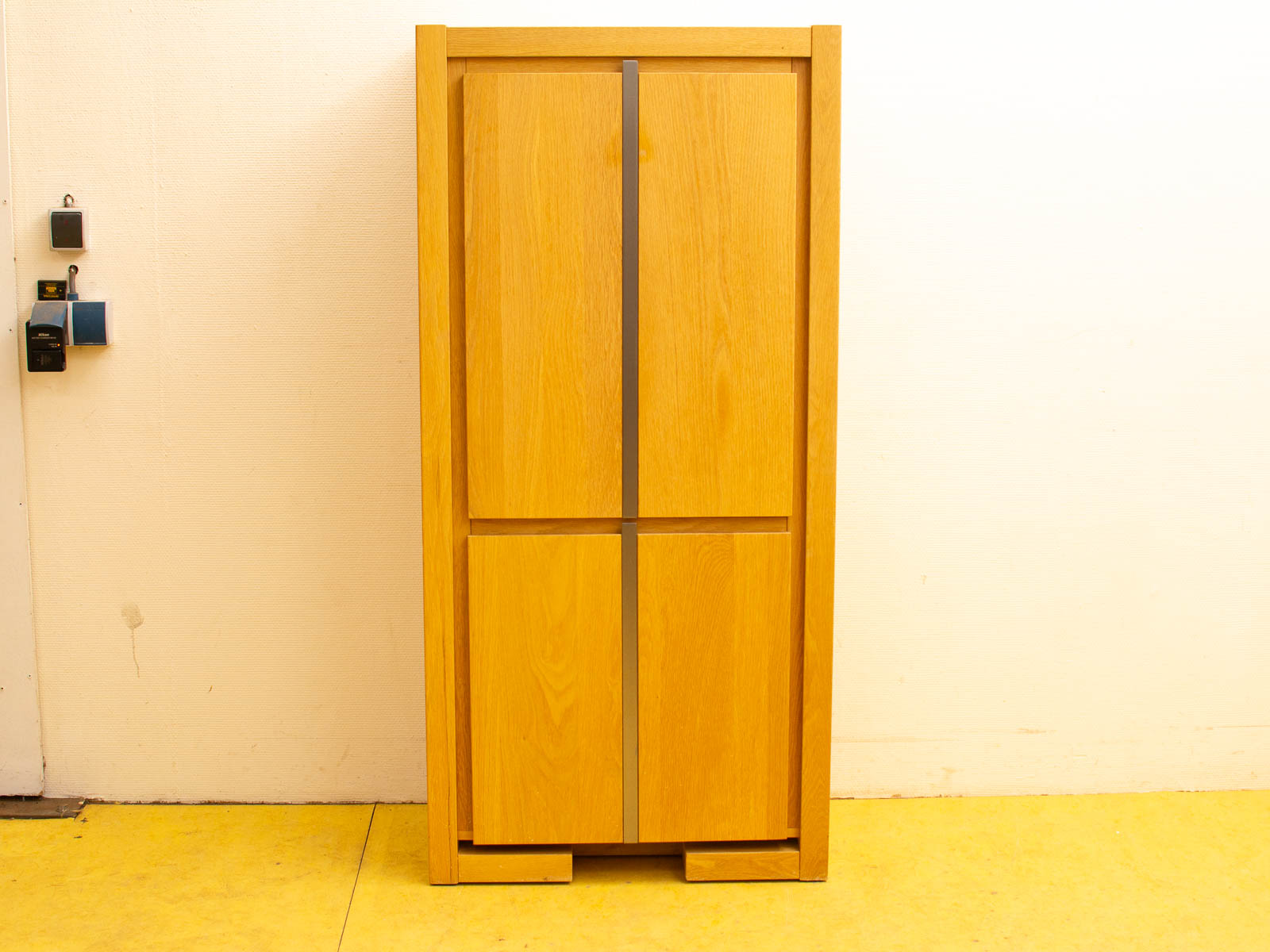 Modern wooden cabinet with minimalist design on yellow floor for stylish, organized storage.