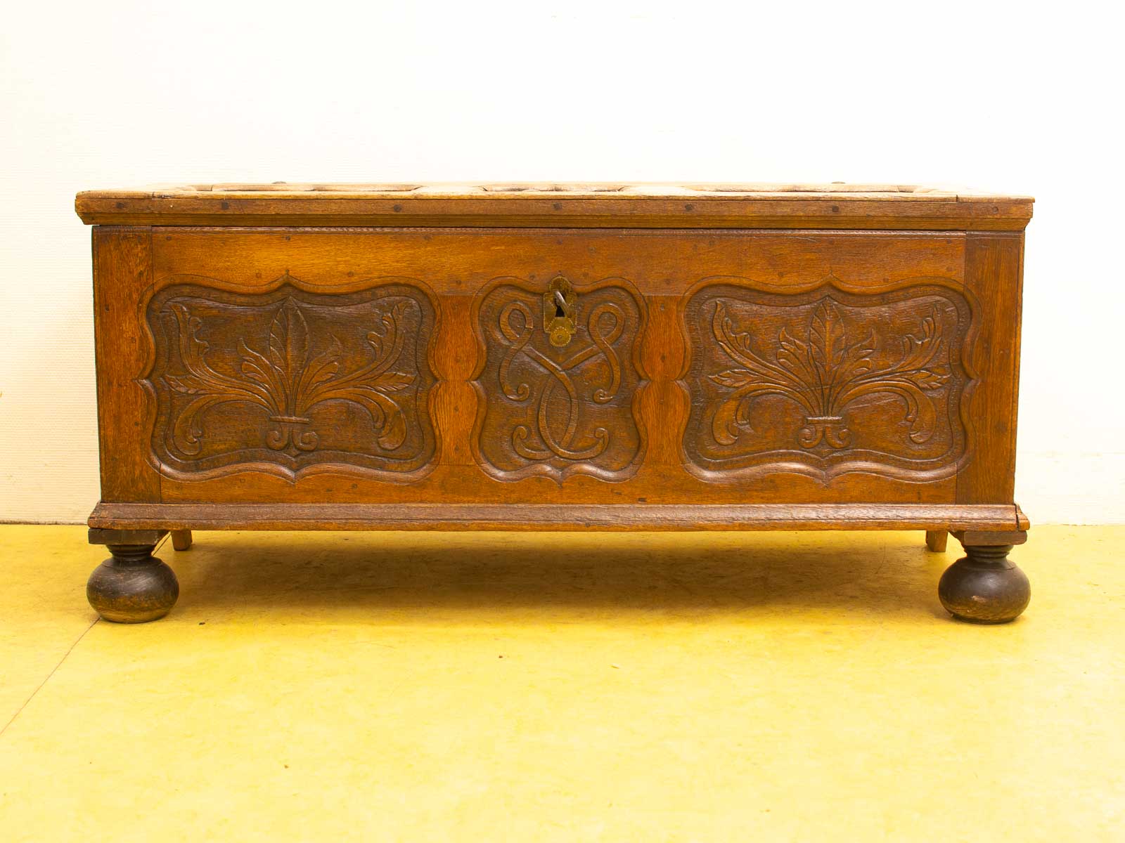 Elegant wooden chest with intricate carvings, rich dark finish, and sturdy legs for stylish storage.