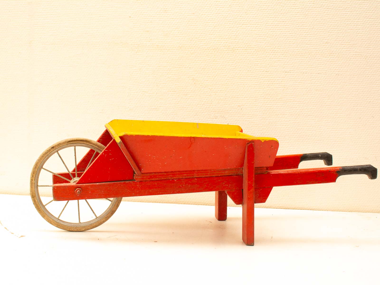 Charming vintage wooden toy wheelbarrow in red and yellow for imaginative play.