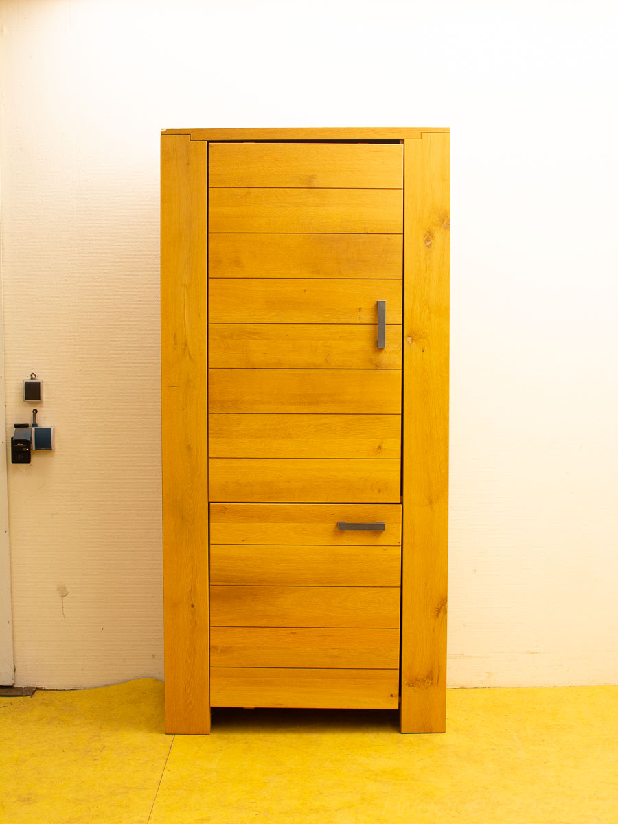 Modern honey-toned wooden cabinet with slats, featuring a vertical door and two spacious drawers.