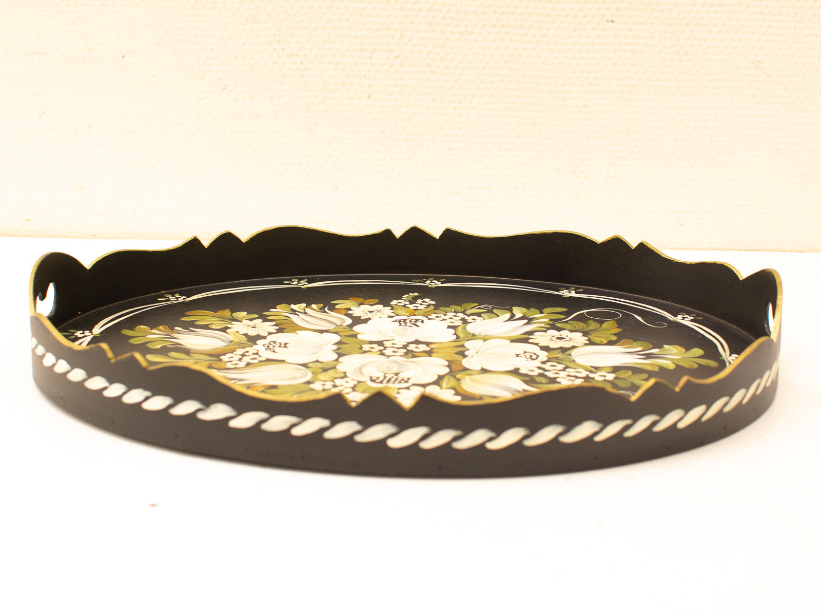 Elegant black round tray with intricate white and green floral designs, perfect for decoration or serving.