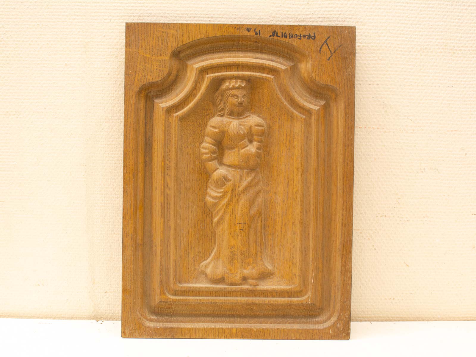 Intricate carved wooden panel with a detailed bas-relief figure in traditional attire.