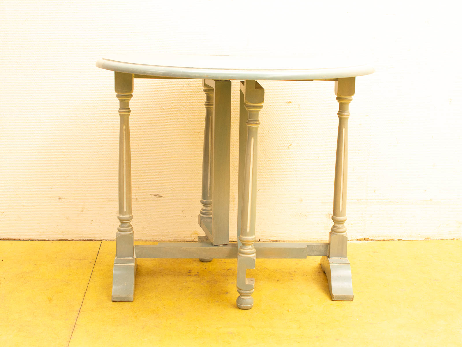 Vintage half-moon table in pastel green wood, perfect for adding charm to any space.