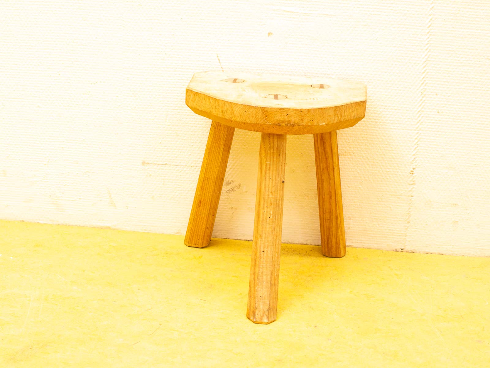 Handcrafted wooden stool with a rounded seat and natural grain, perfect for any decor.