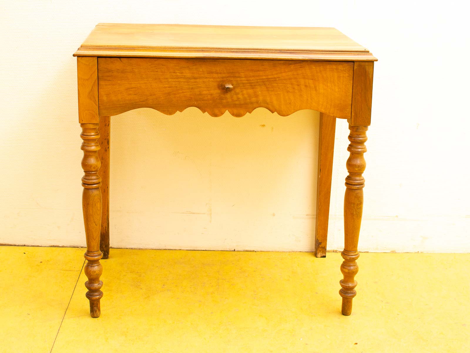 Elegant wooden table with drawer and turned legs, perfect for various interior styles.