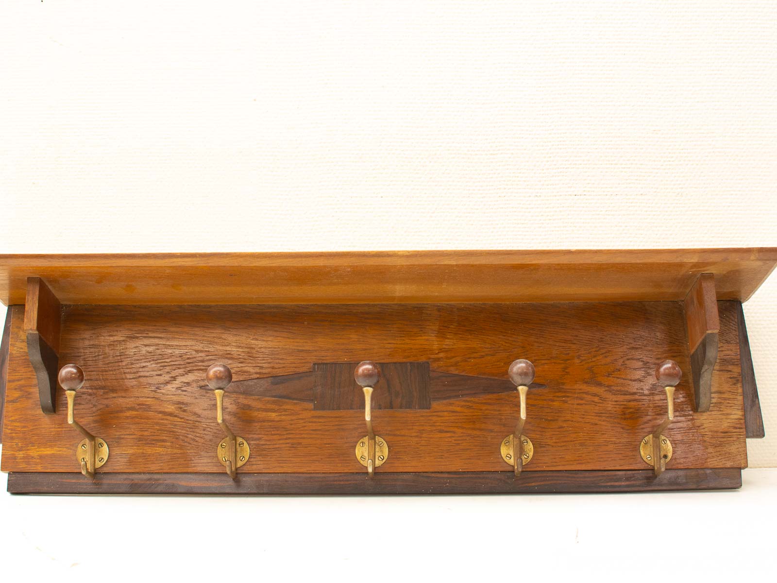 Vintage wooden wall hook rack with brass hooks and shelf, ideal for enhancing entryways.