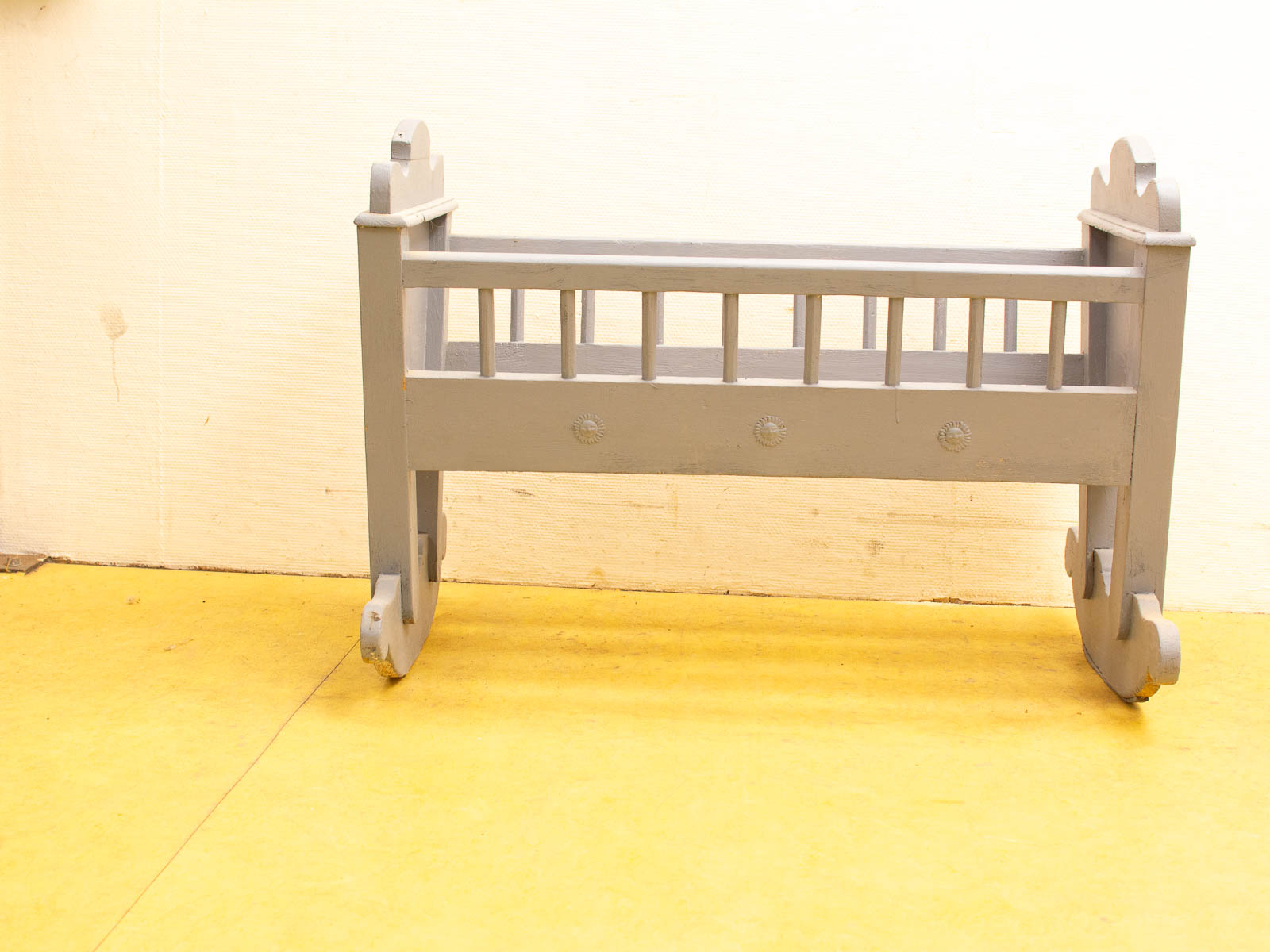 Charming gray wooden crib with circular motif, perfect for modern or vintage nurseries.