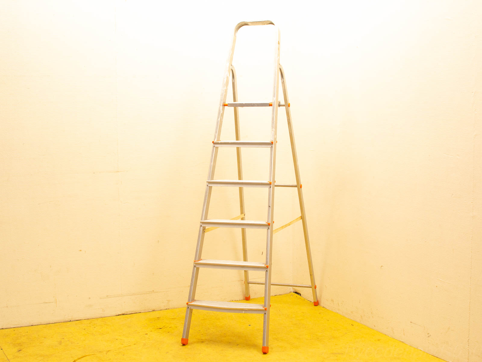 Sturdy aluminum step ladder with handrail, perfect for reaching high spaces in any workspace.