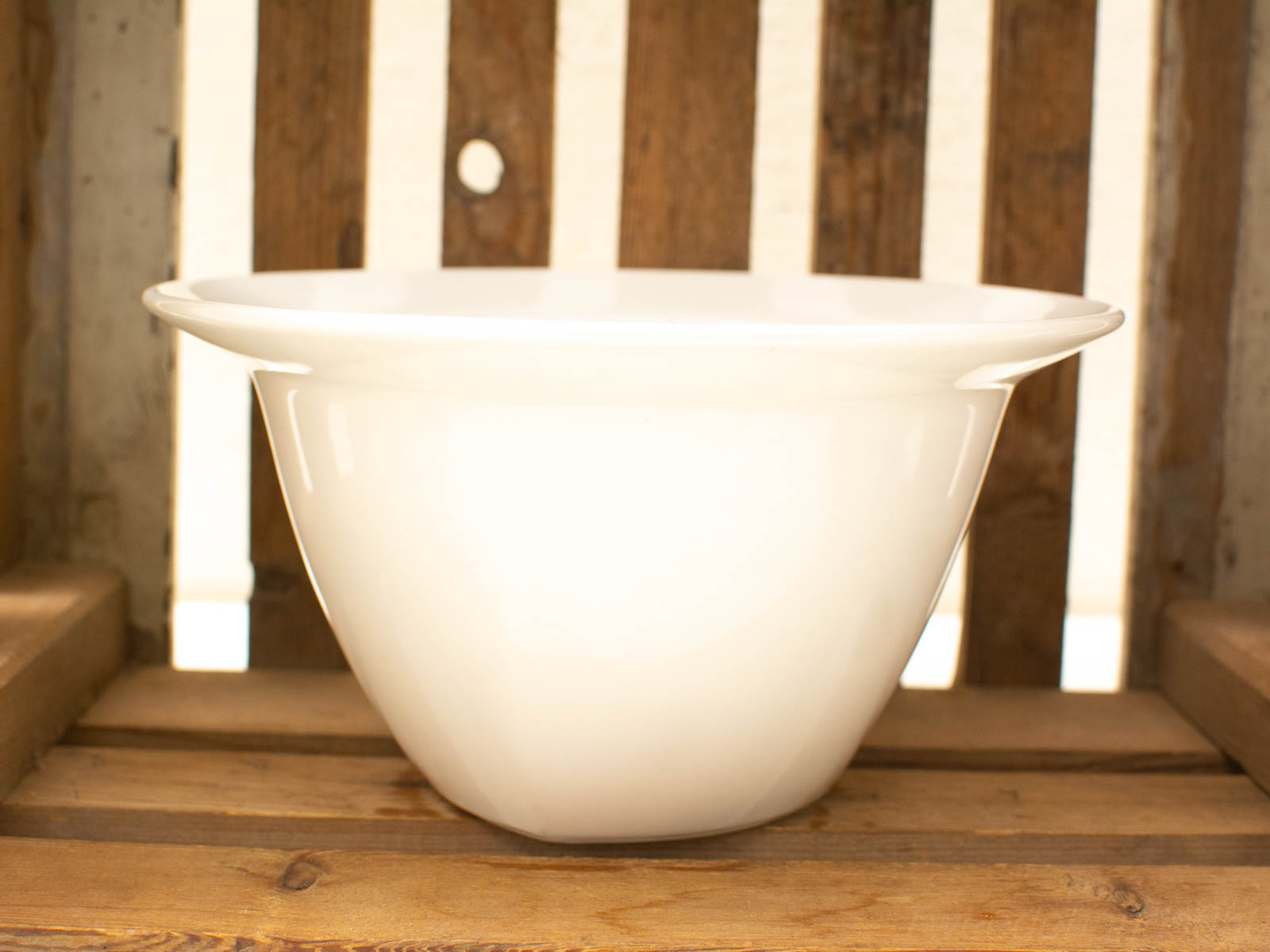 Elegant white bowl on rustic wooden table, blending modern design with natural charm.