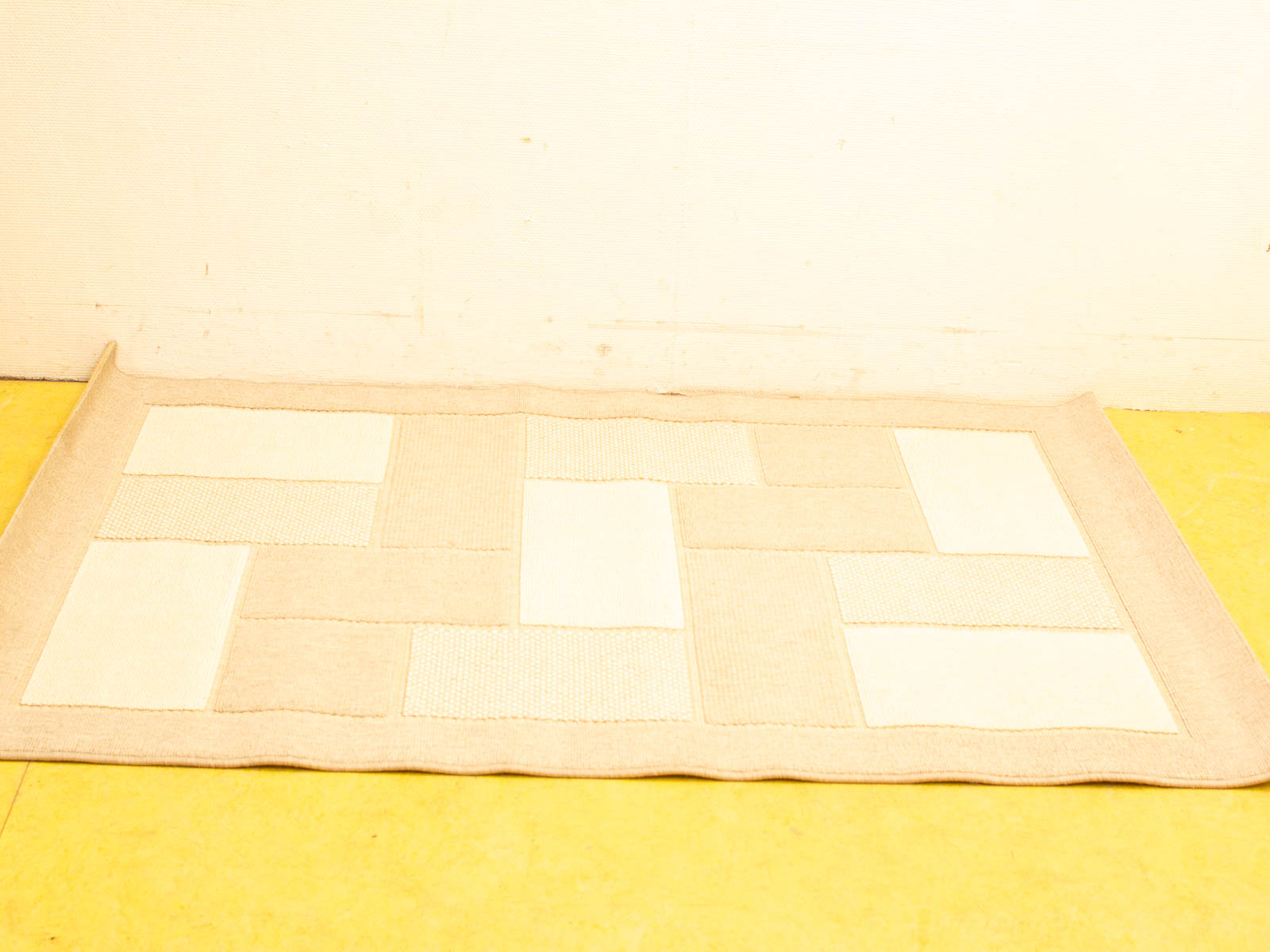 Elegant beige patchwork rug on a sunny yellow floor, enhancing any interior style.