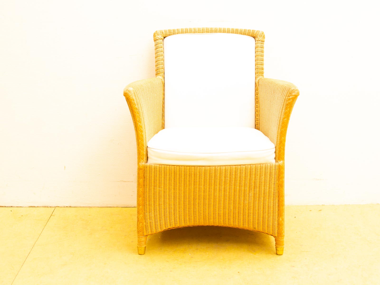 Chic woven rattan armchair with plush white cushion for stylish comfort in any setting.