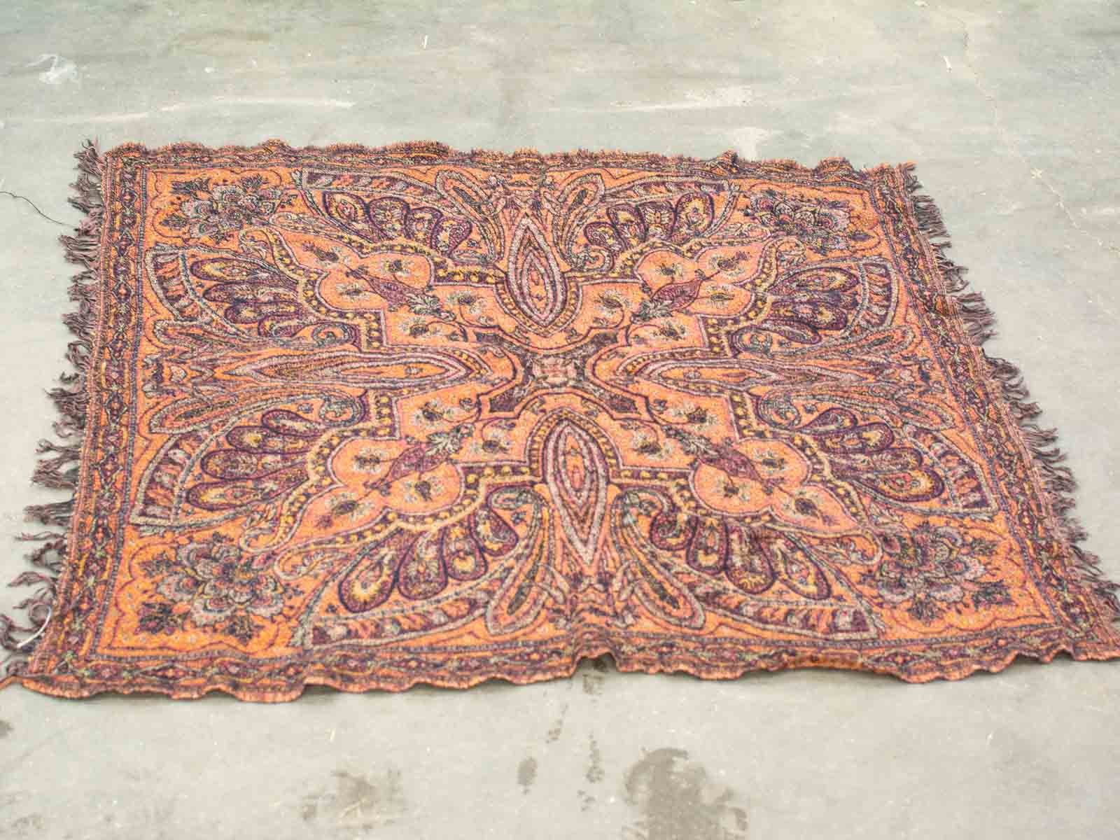 Handwoven vintage rug with warm orange and brown hues, featuring intricate floral patterns.