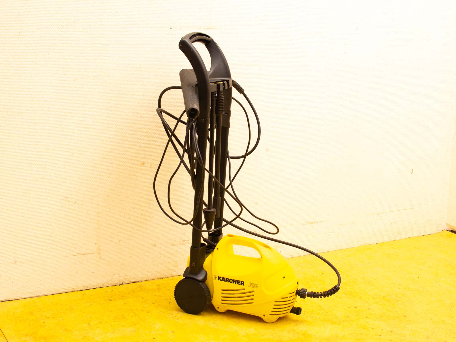 Compact Kärcher high-pressure washer in yellow, ideal for outdoor cleaning and easy storage.