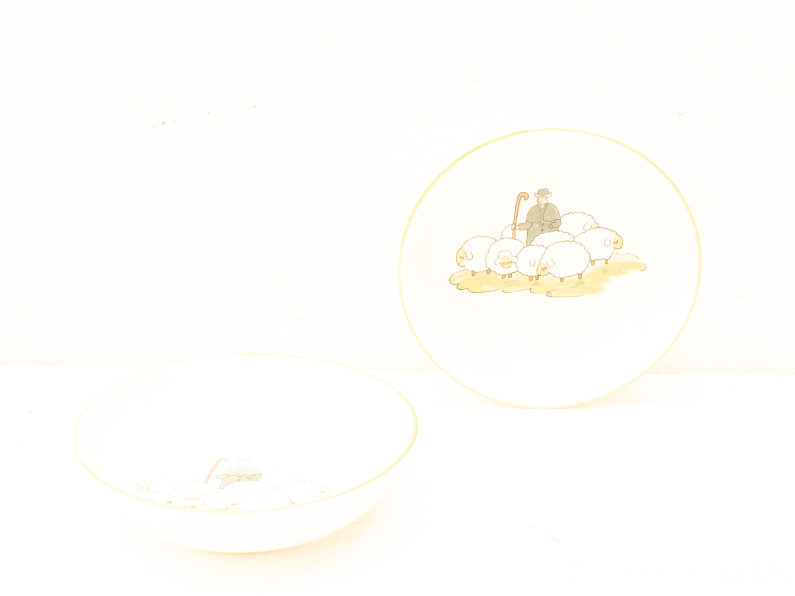 Charming ceramic bowls with shepherd and sheep illustrations, perfect for rustic dining decor.