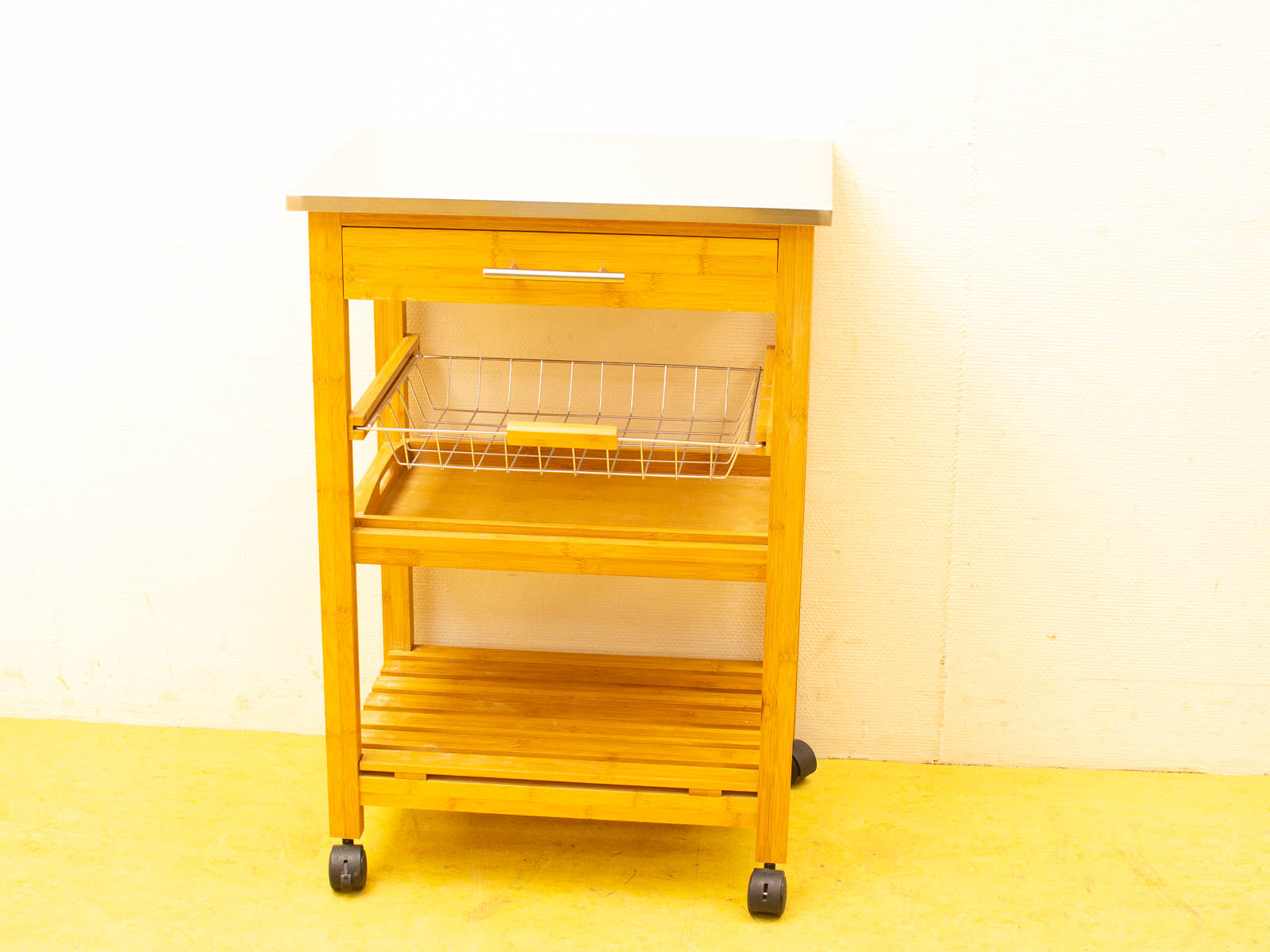 Versatile bamboo kitchen cart with wheels, stainless steel top, drawer, and wire basket for storage.