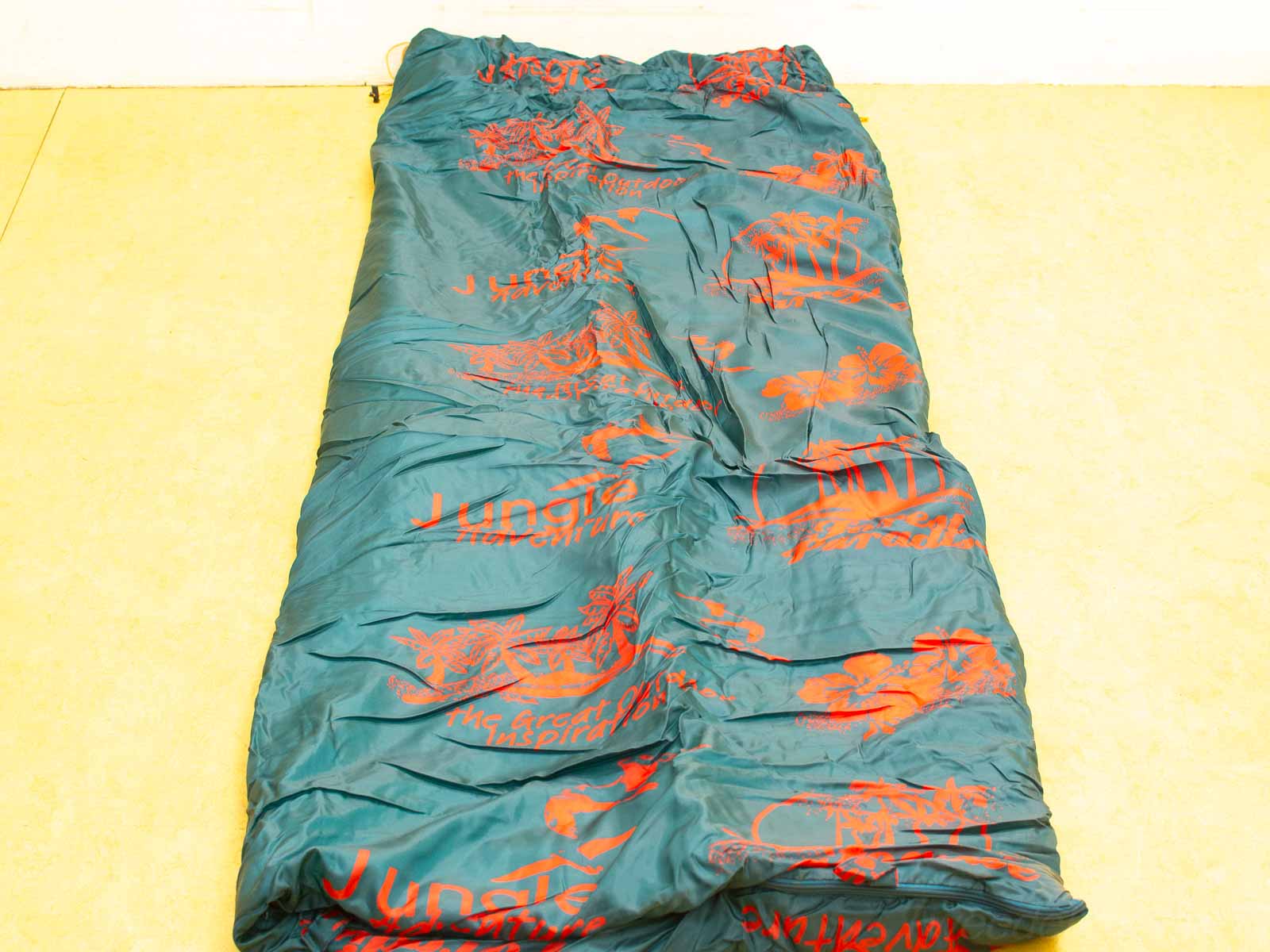 Teal sleeping bag with vibrant orange tropical designs, perfect for camping and outdoor adventures.