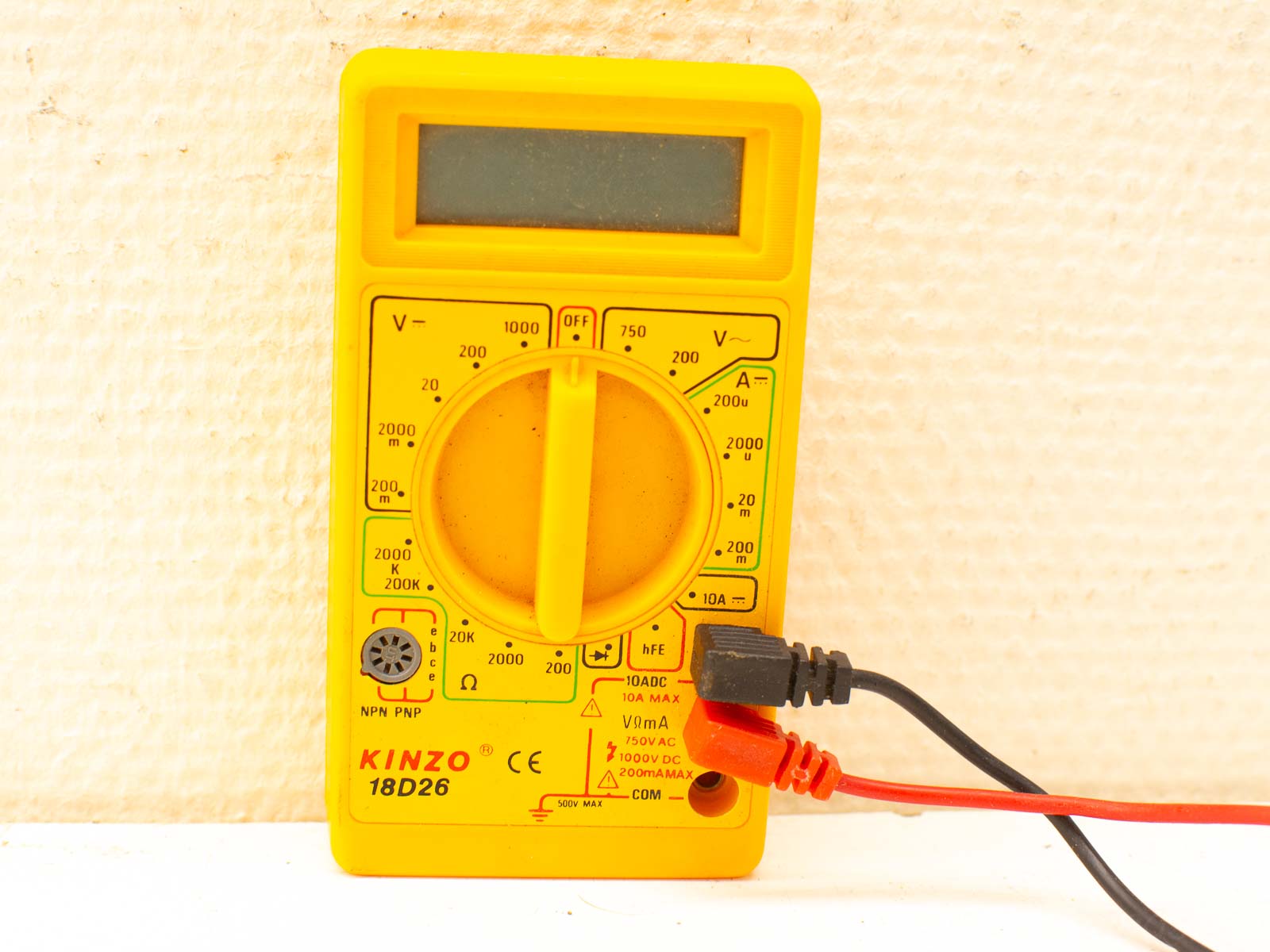 Yellow digital multimeter with test leads for voltage, current, and resistance measurements.