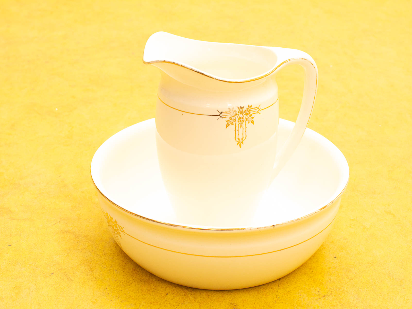 Elegant vintage ceramic pitcher and basin set with gold accents, perfect for decor or collection.