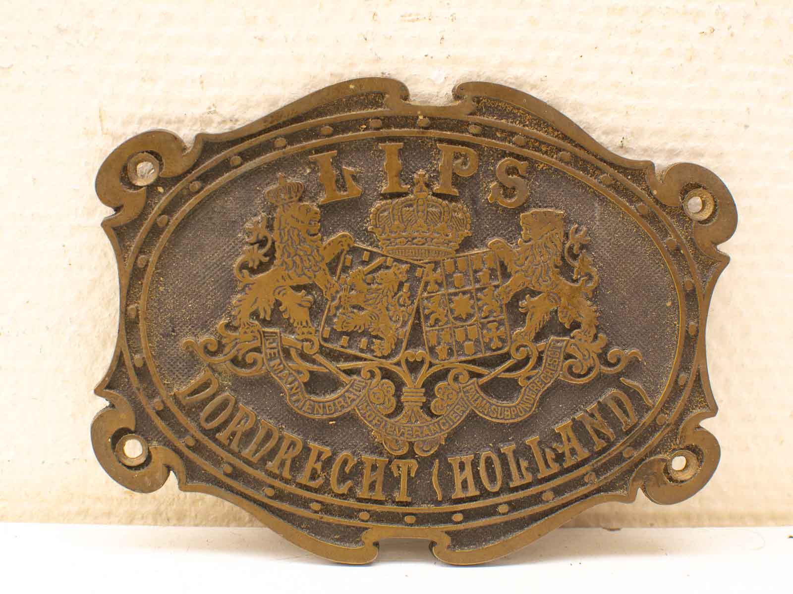 Vintage brass plaque with heraldic lions and Dordrecht emblem, symbolizing history and nobility.