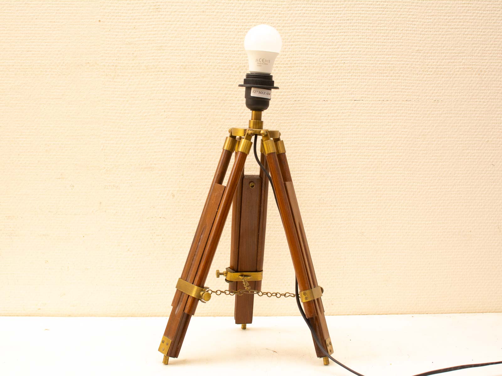 Stylish vintage tripod lamp with polished wooden legs and brass fittings for a cozy ambiance.