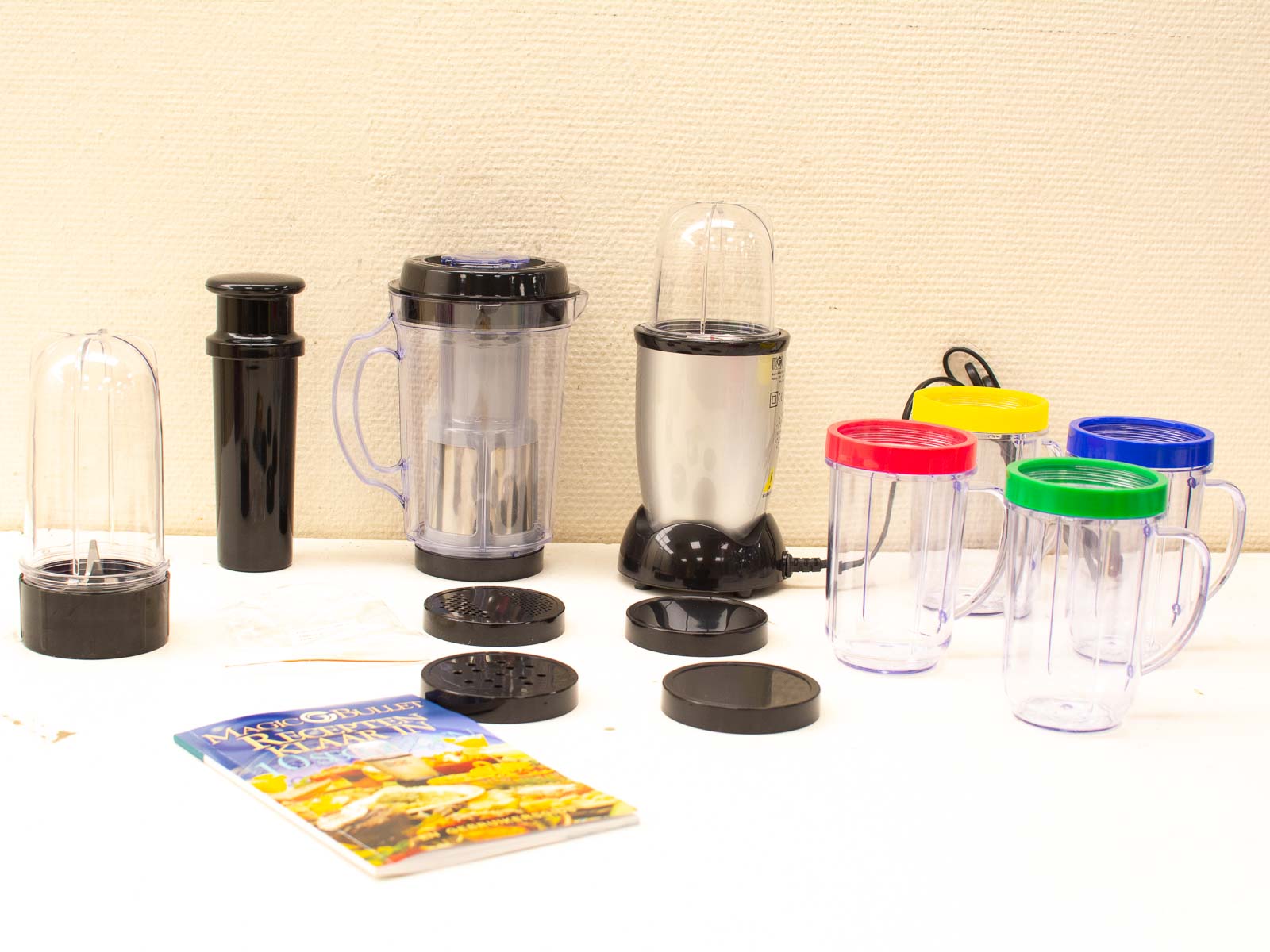 Stylish silver blender set with colorful cups and healthy recipe book for creative cooking.