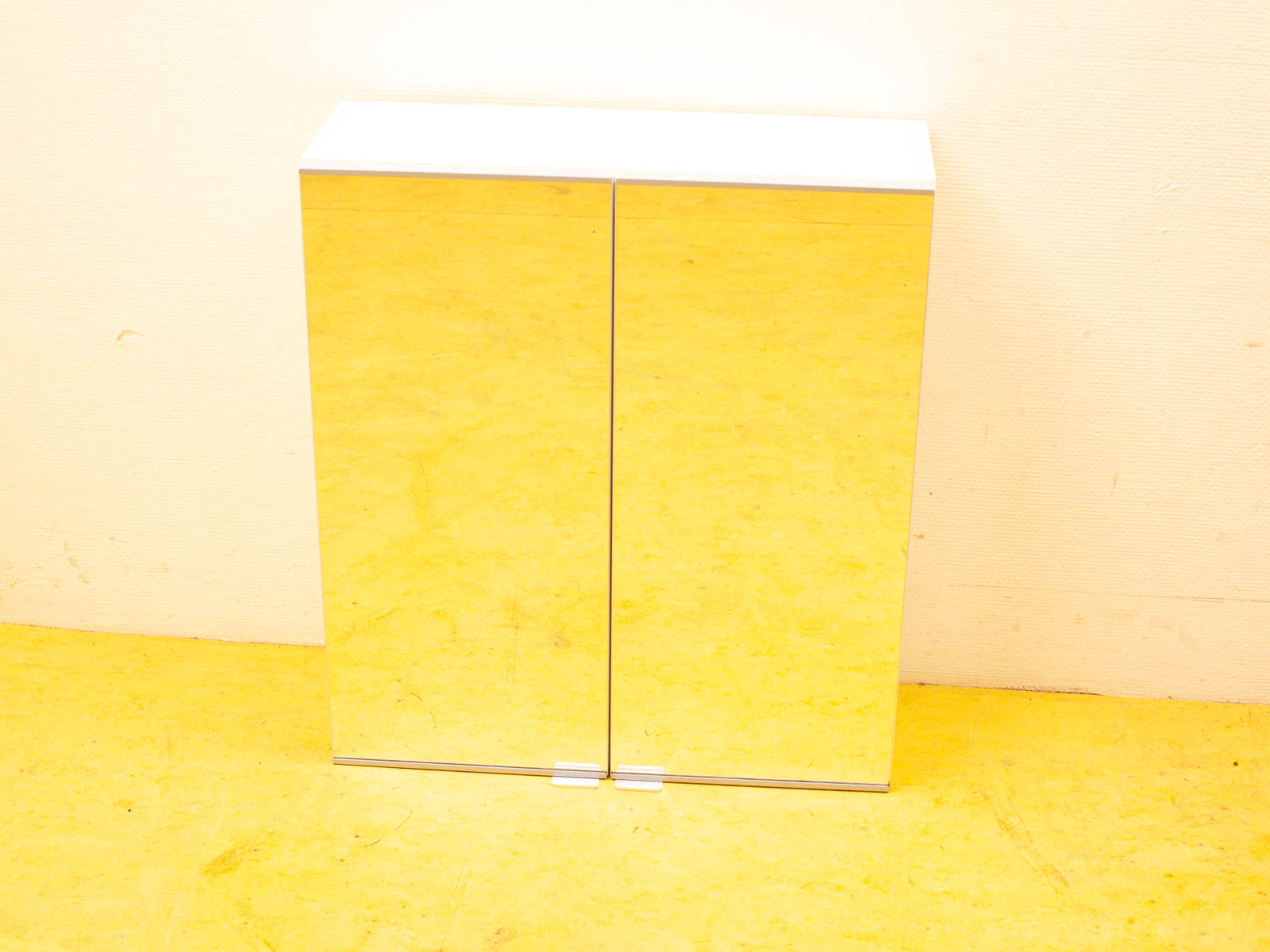 Stylish mirrored cabinet with white top and yellow floor, perfect for modern interiors.