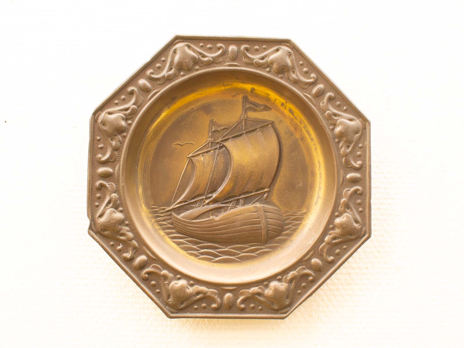 Exquisite octagonal plate featuring a carved sailing ship, perfect for nautical decor enthusiasts.