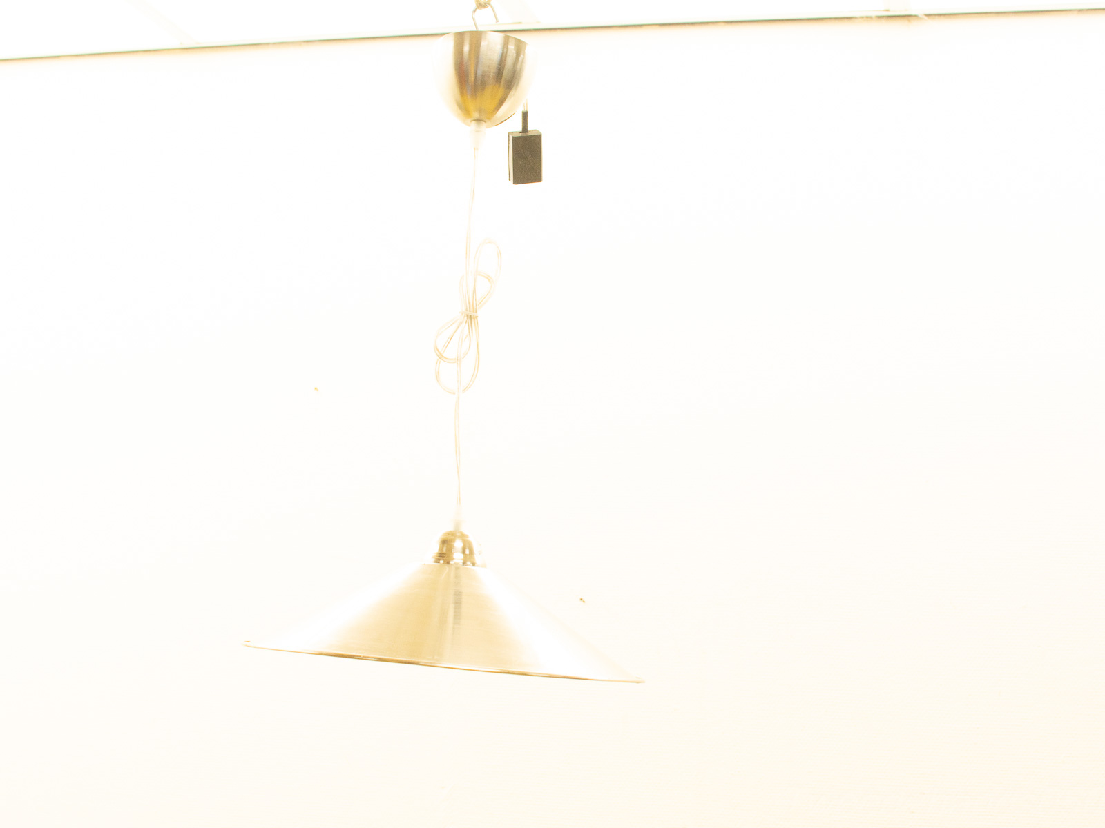 Sleek conical pendant light in polished metal for modern dining, kitchen, or cafe interiors.