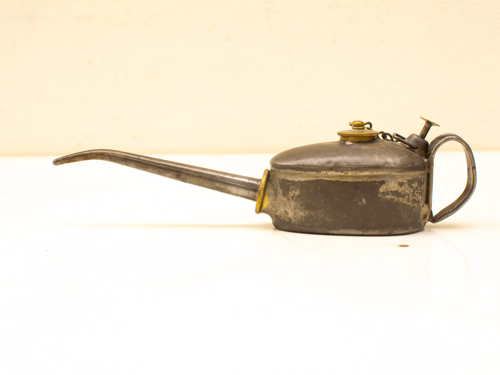 Antique oil can with brass accents, featuring a curved spout and vintage design.