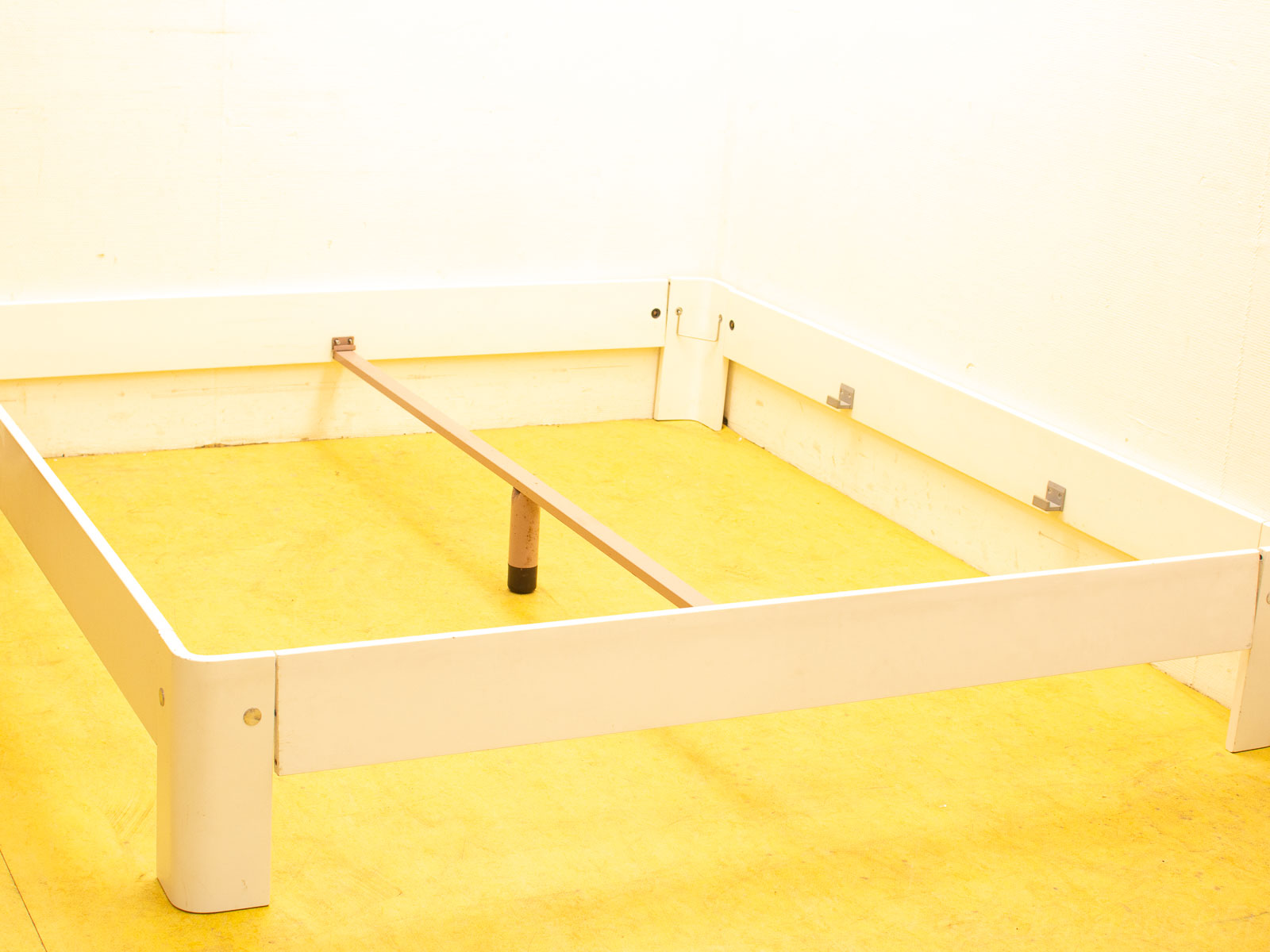 Minimalist bed frame on cheerful yellow floor, perfect for modern and stylish bedroom decor.