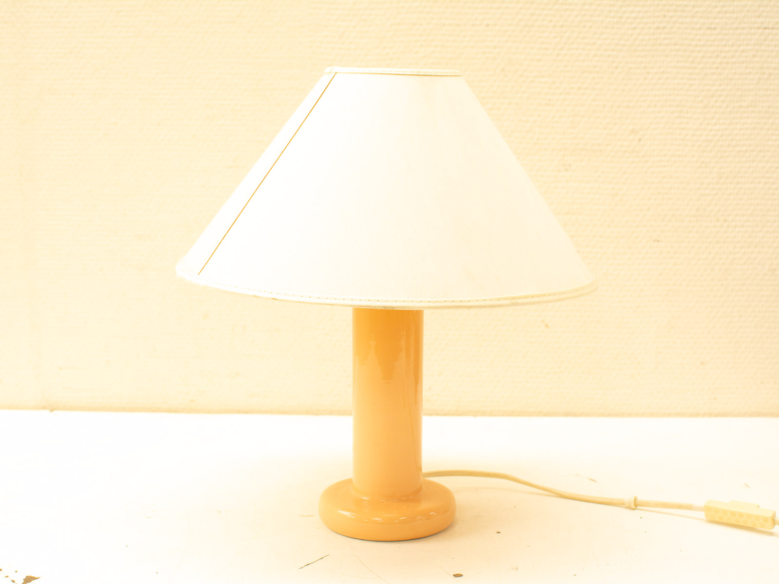 Charming peach-orange table lamp with a white fabric shade and golden trim, perfect for modern interiors.