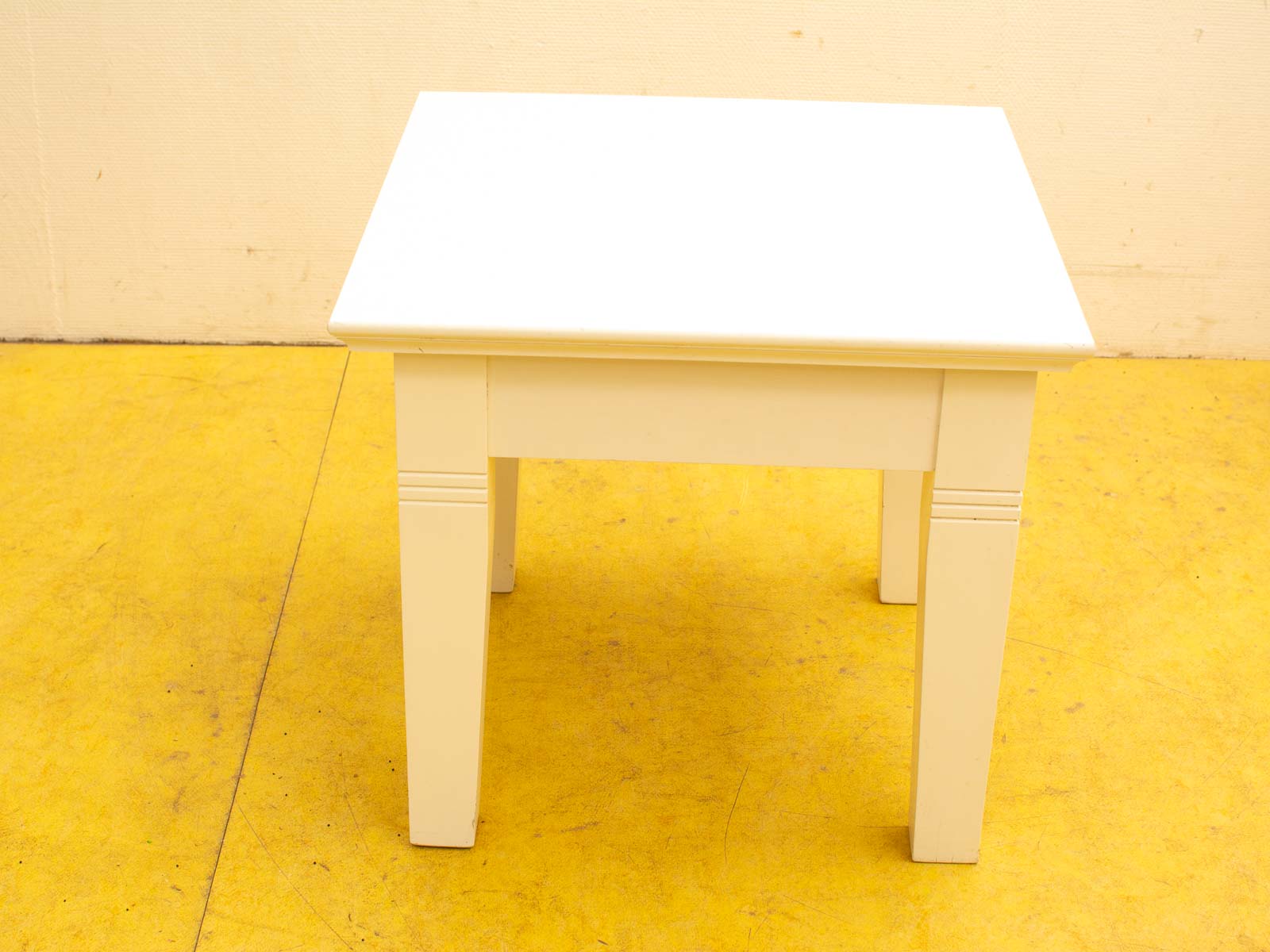 Elegant off-white square table with cheerful yellow background, perfect for versatile interior styles.