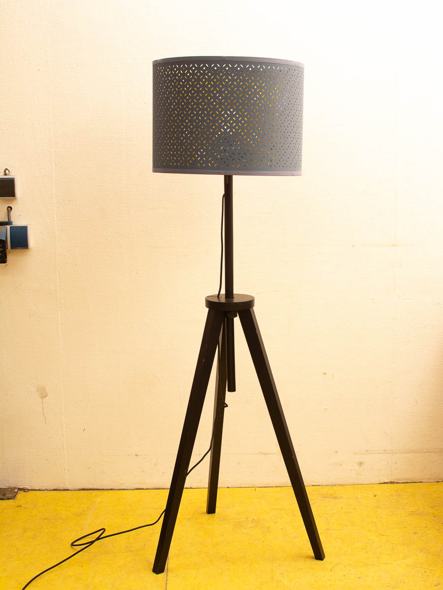 Stylish tripod floor lamp with perforated shade on vibrant yellow flooring for modern interiors.