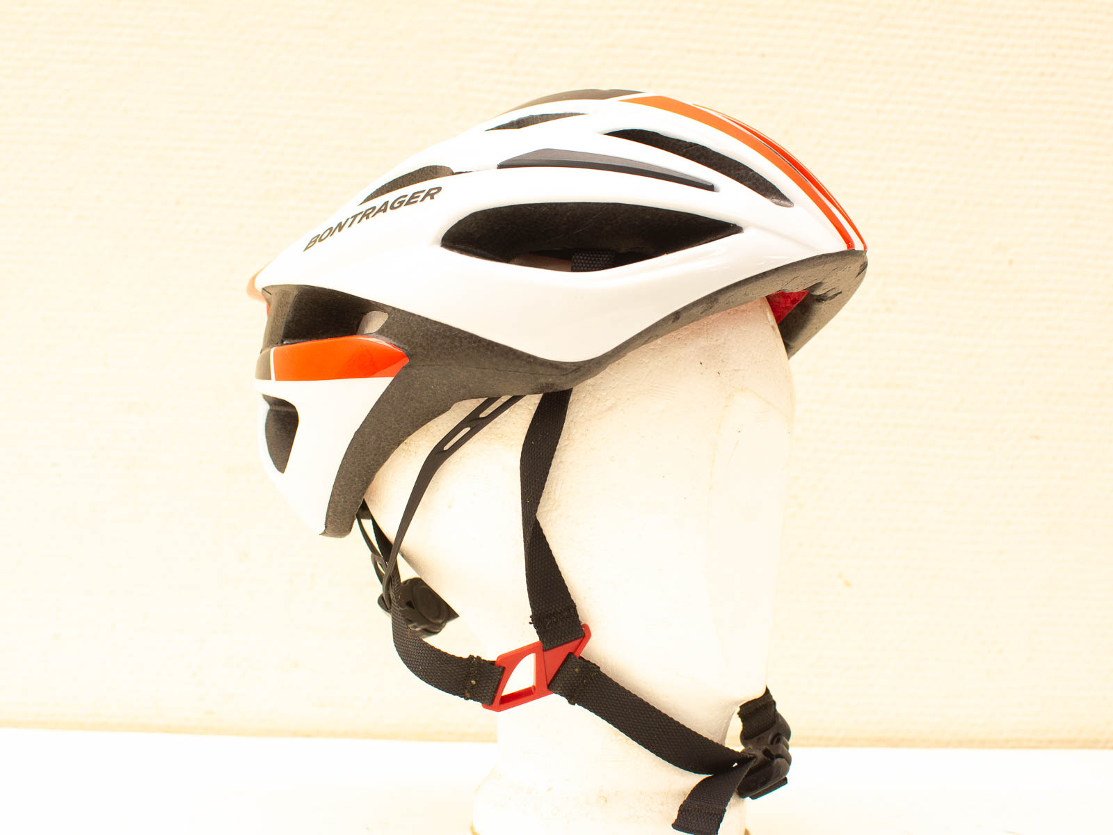 Sleek white bicycle helmet with ventilation, orange accents, and safety features for cyclists.