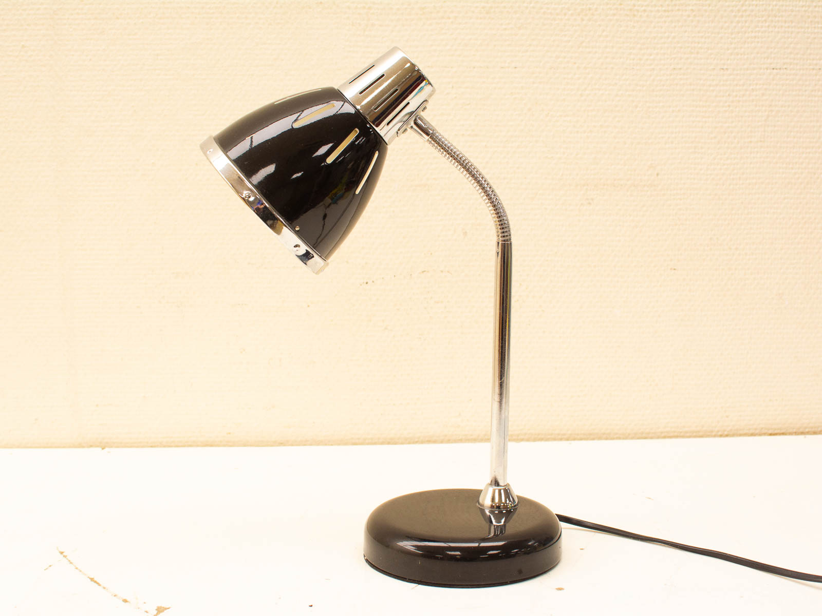 Stylish black desk lamp with chrome accents and adjustable gooseneck for modern workspaces.