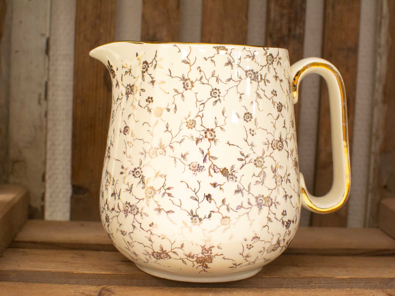 Elegant vintage ceramic pitcher with floral design, glossy finish, and gold trim for stylish decor.