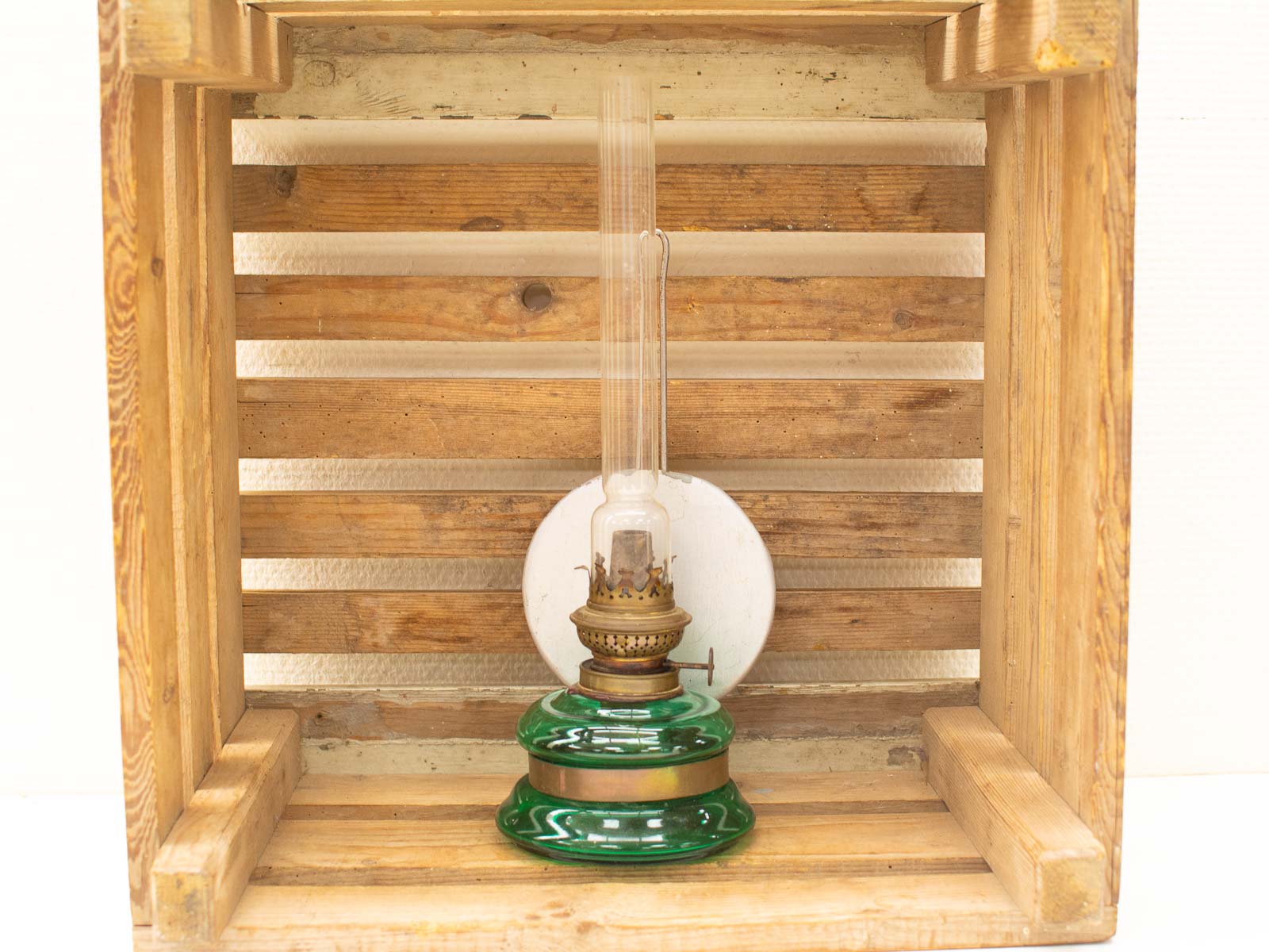 Charming vintage oil lamp in rustic wooden crate, evoking nostalgia and warm ambiance.