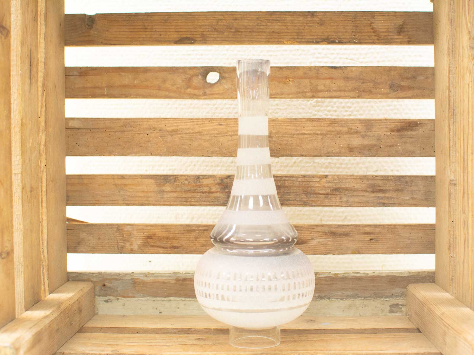 Elegant glass vase with rustic wooden backdrop, perfect for sophisticated home decor.