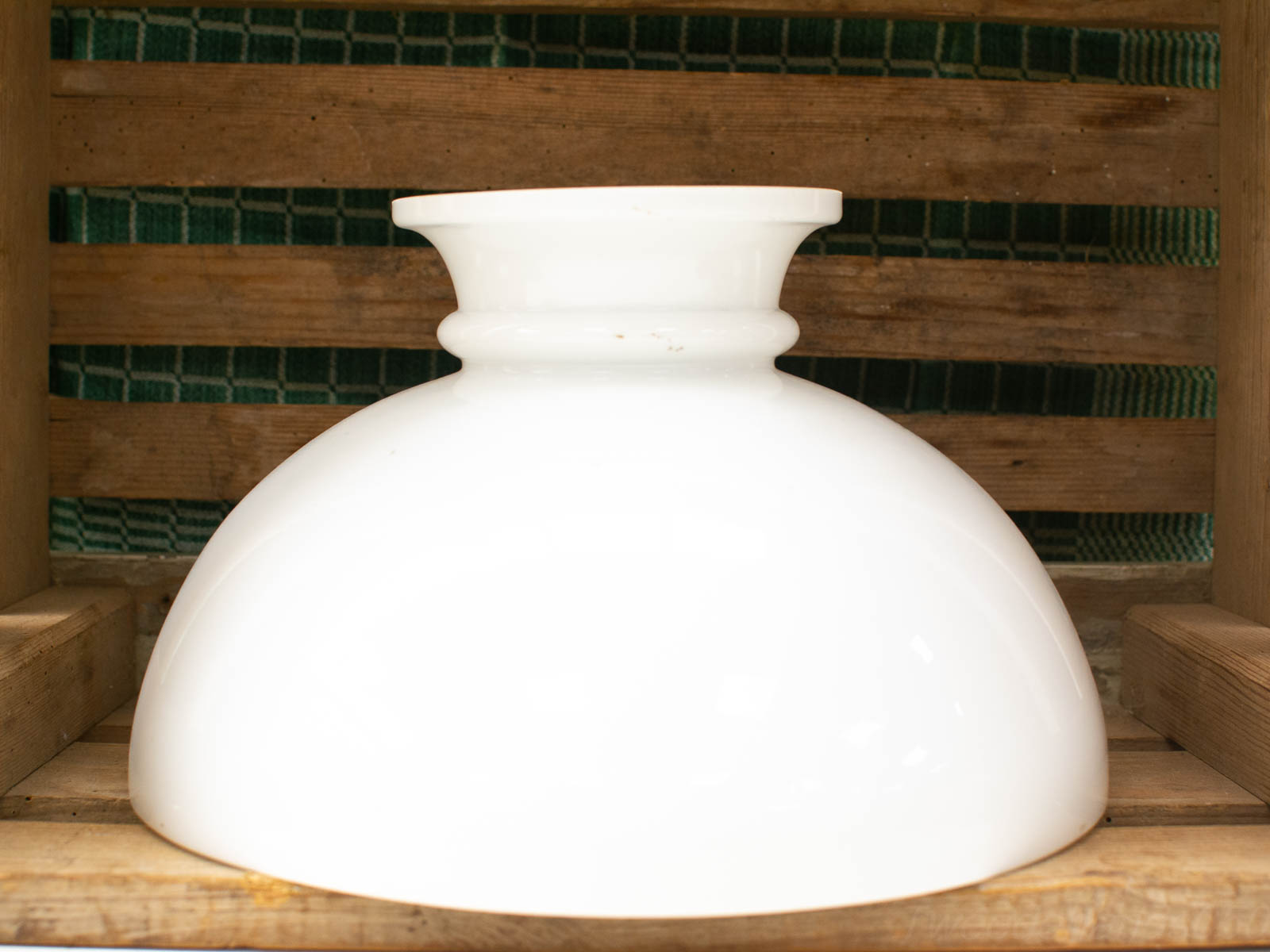 Elegant white ceramic bowl on wooden shelf with green textured background. Perfect for decor and function.