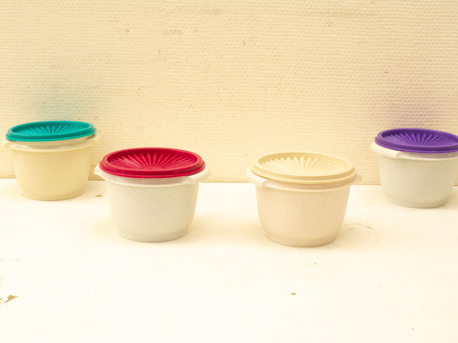 Vibrant storage containers with unique vintage lids, perfect for colorful kitchen organization.