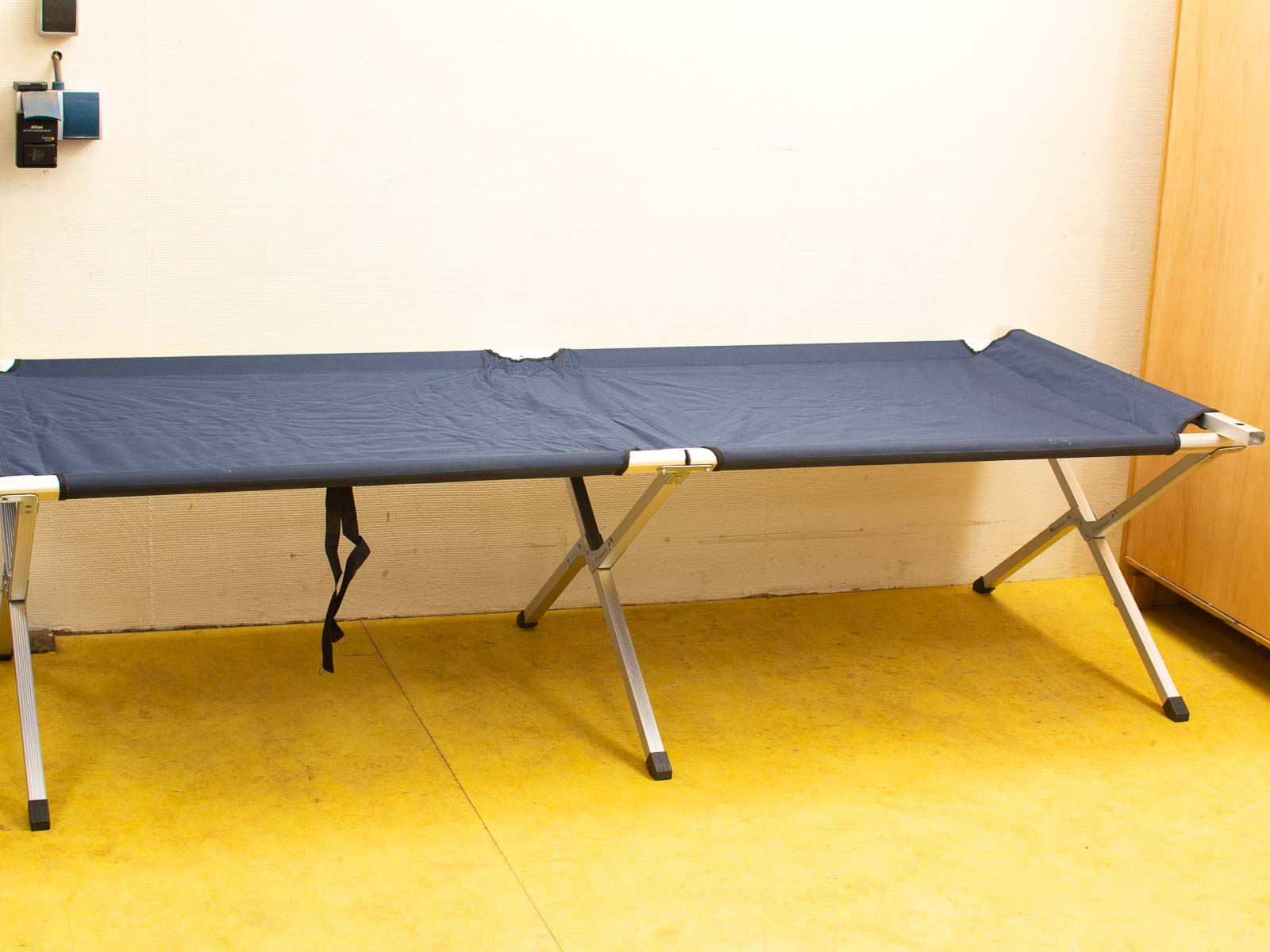 Navy blue folding cot with lightweight aluminum frame, ideal for camping and temporary use.