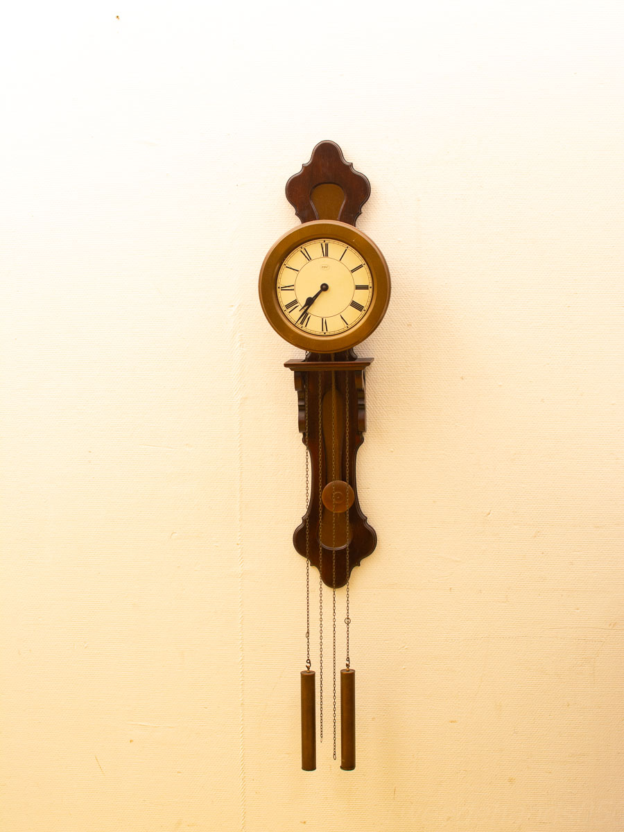 Elegant wooden wall clock with pendulums and Roman numerals, perfect for vintage decor.