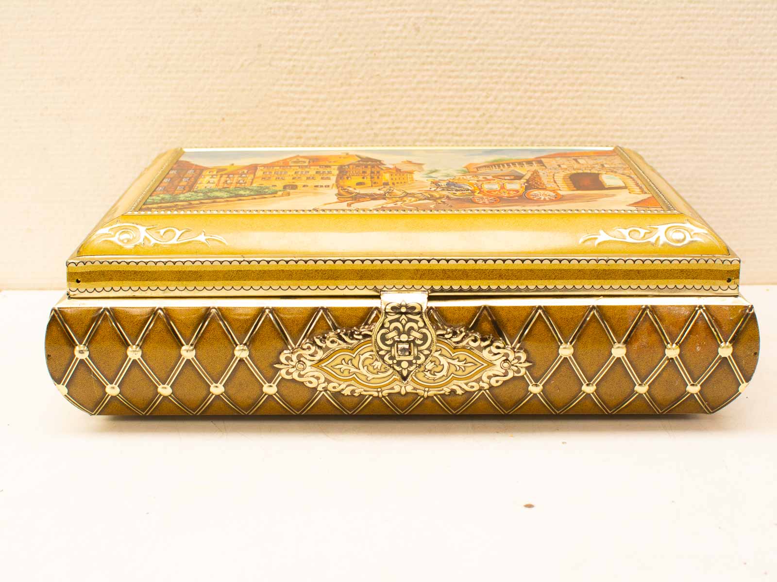 Elegant vintage gold box with painted scene, intricate details, and ornate clasp for storage or decor.