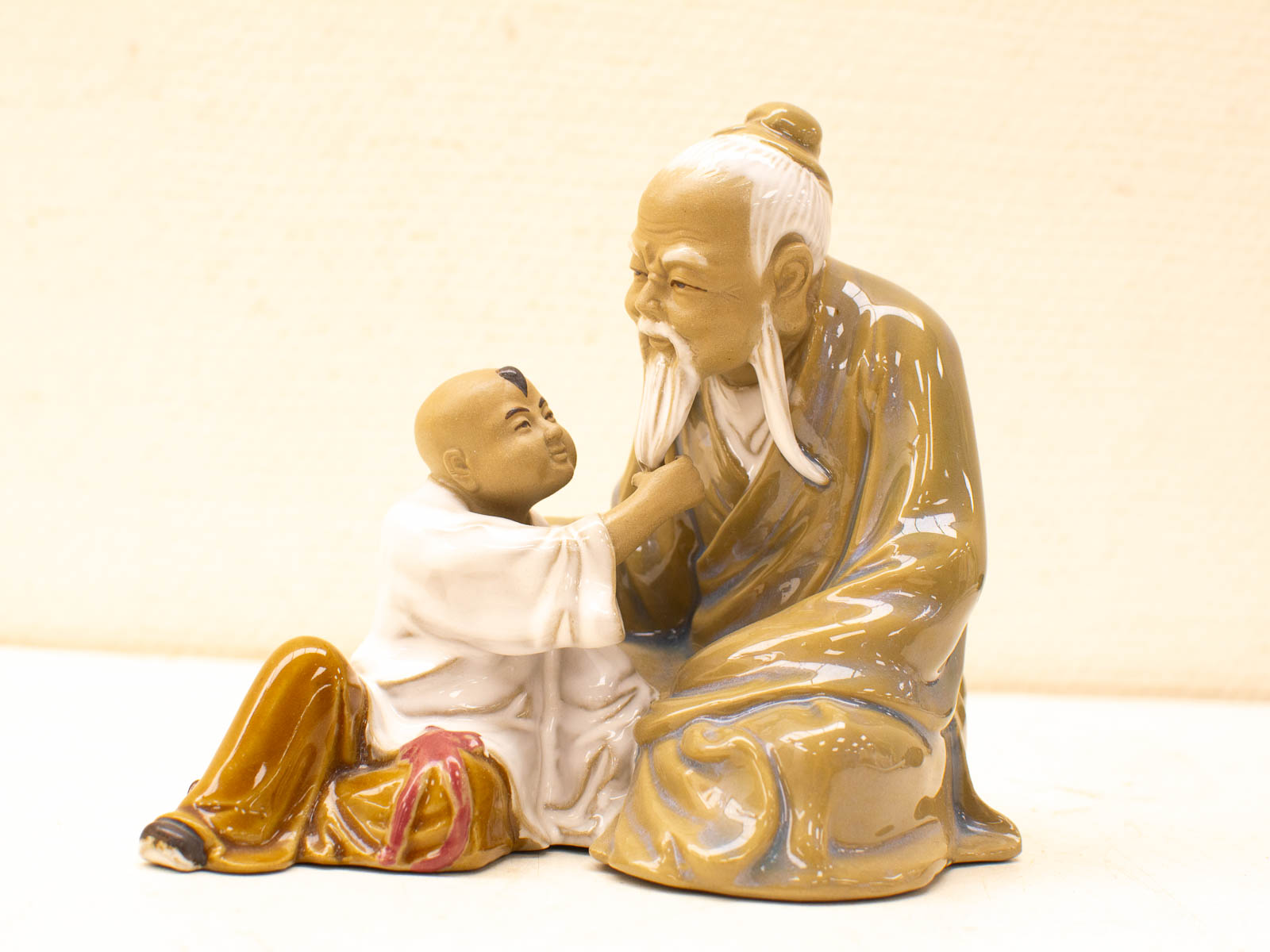 Vintage ceramic figurine of an elderly man and young boy, symbolizing wisdom and playful curiosity.